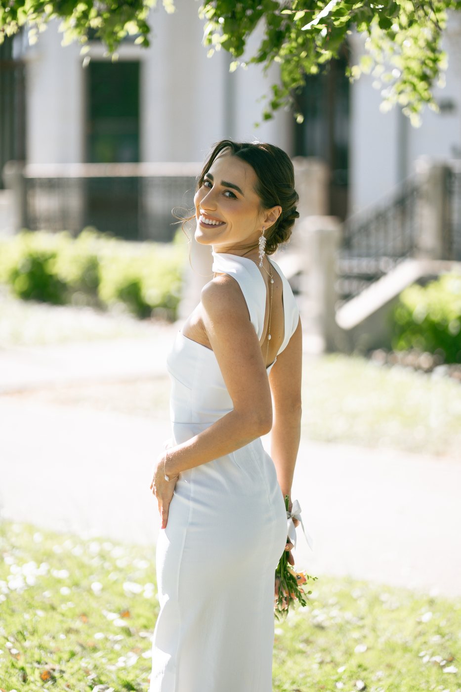 Mariée en robe blanche dans un jardin, chignon bas et maquillage naturel