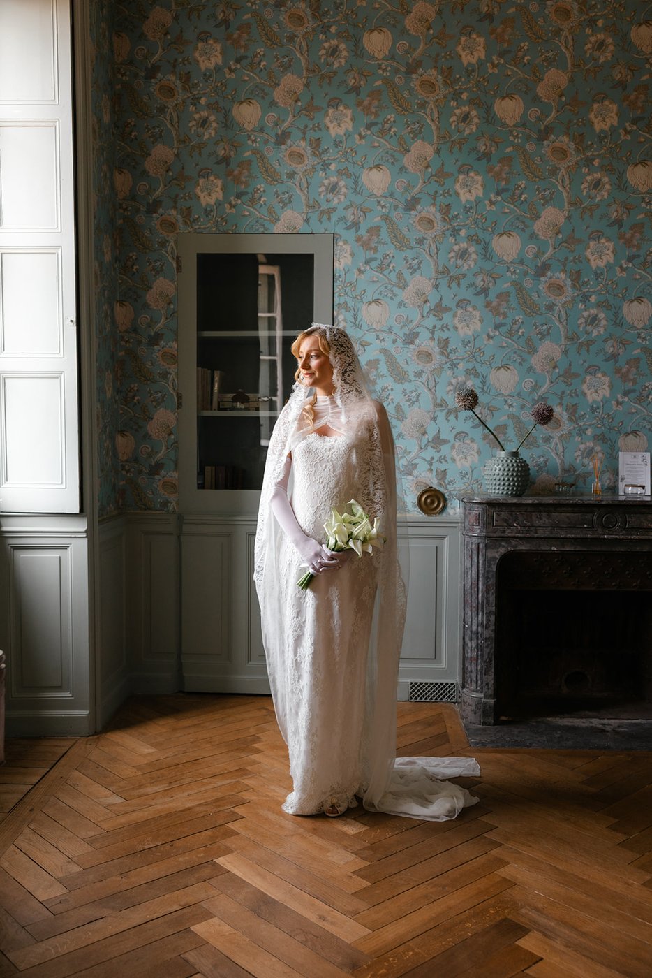 Mariée en cape de dentelle avec bouquet d'arums, préparatifs en château