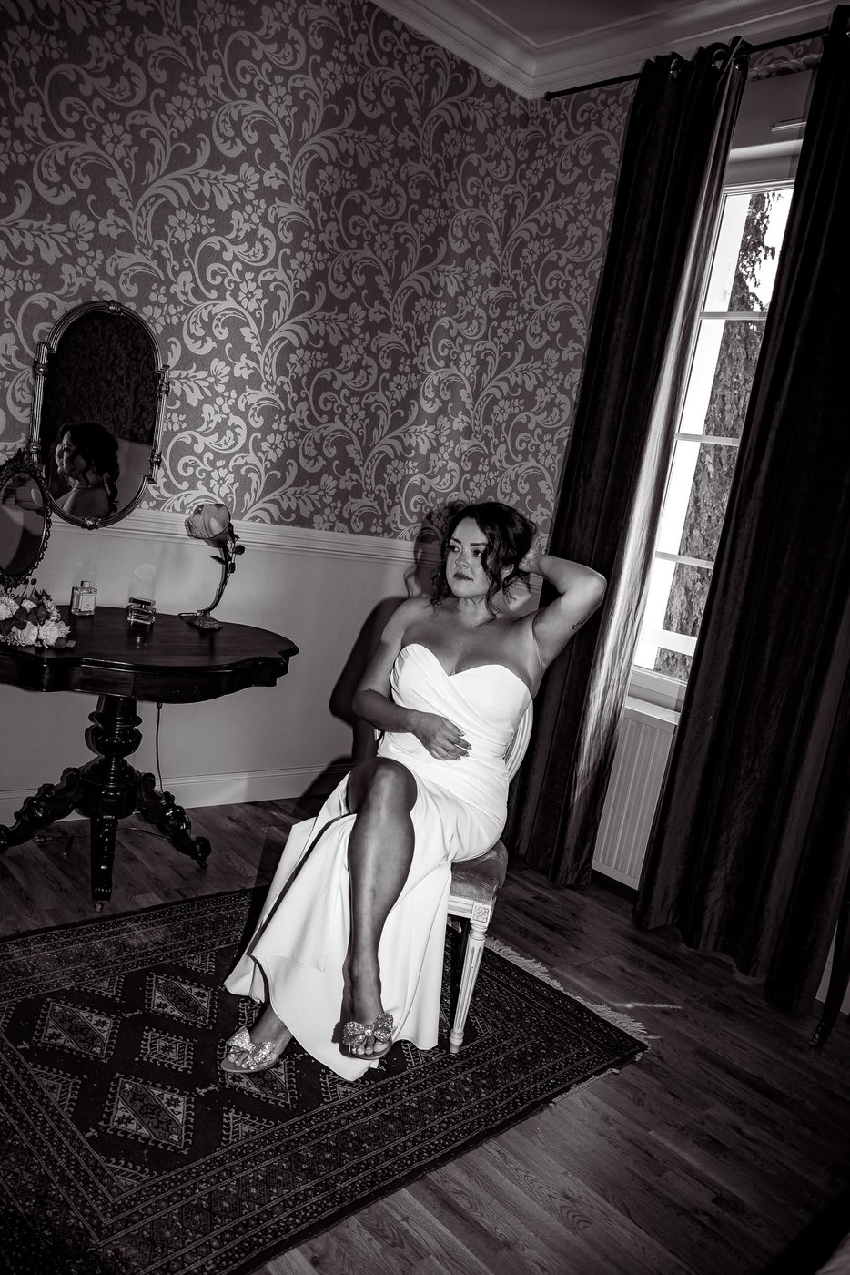 Mariée en robe fourreau assise près d'une fenêtre, noir et blanc