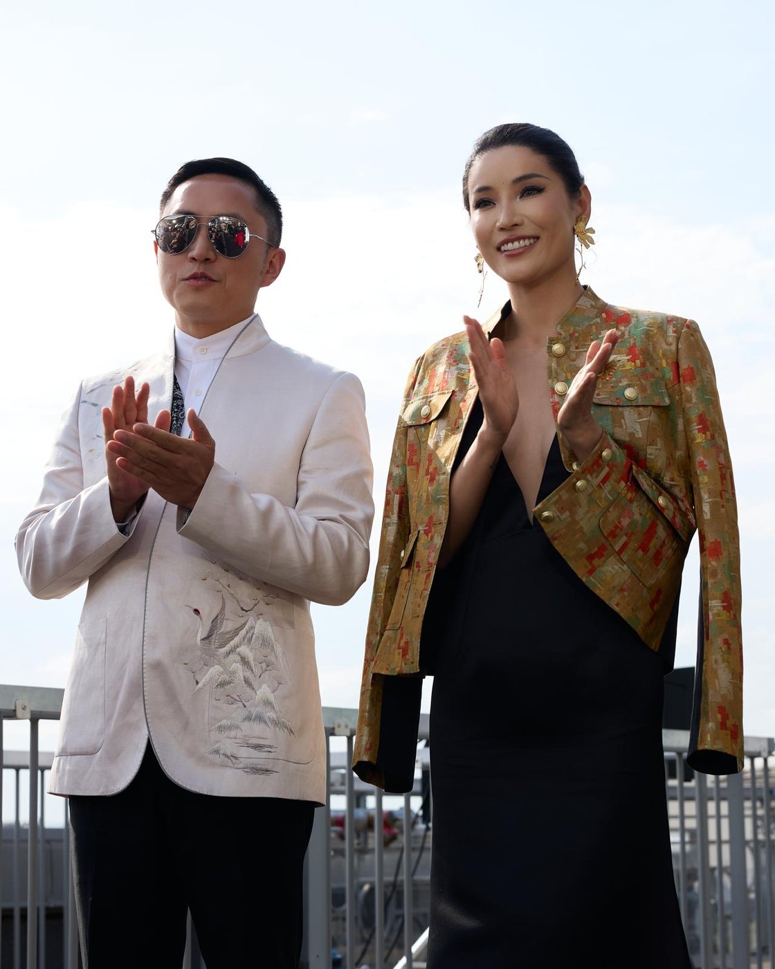 Couple applaudissant lors d'un événement mode, maquillage de soirée longue tenue